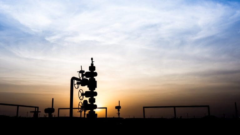 The silhouette of a wellhead at dusk