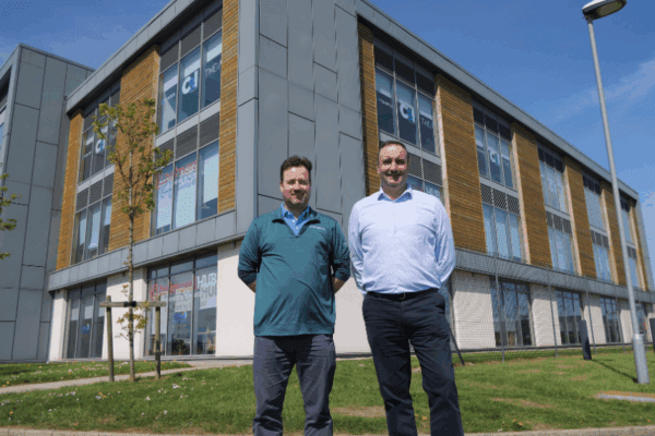 Two men stand outside an office facility