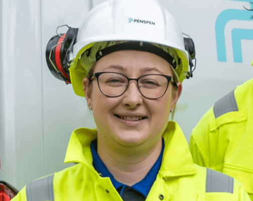 A female engineer in PPE and glasses is smiling at the camea