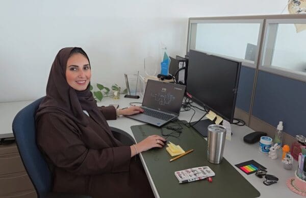 A woman sat at a desk with computer screens