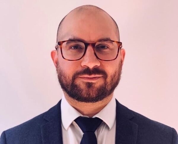 A man wearing a suit and tie and glasses.