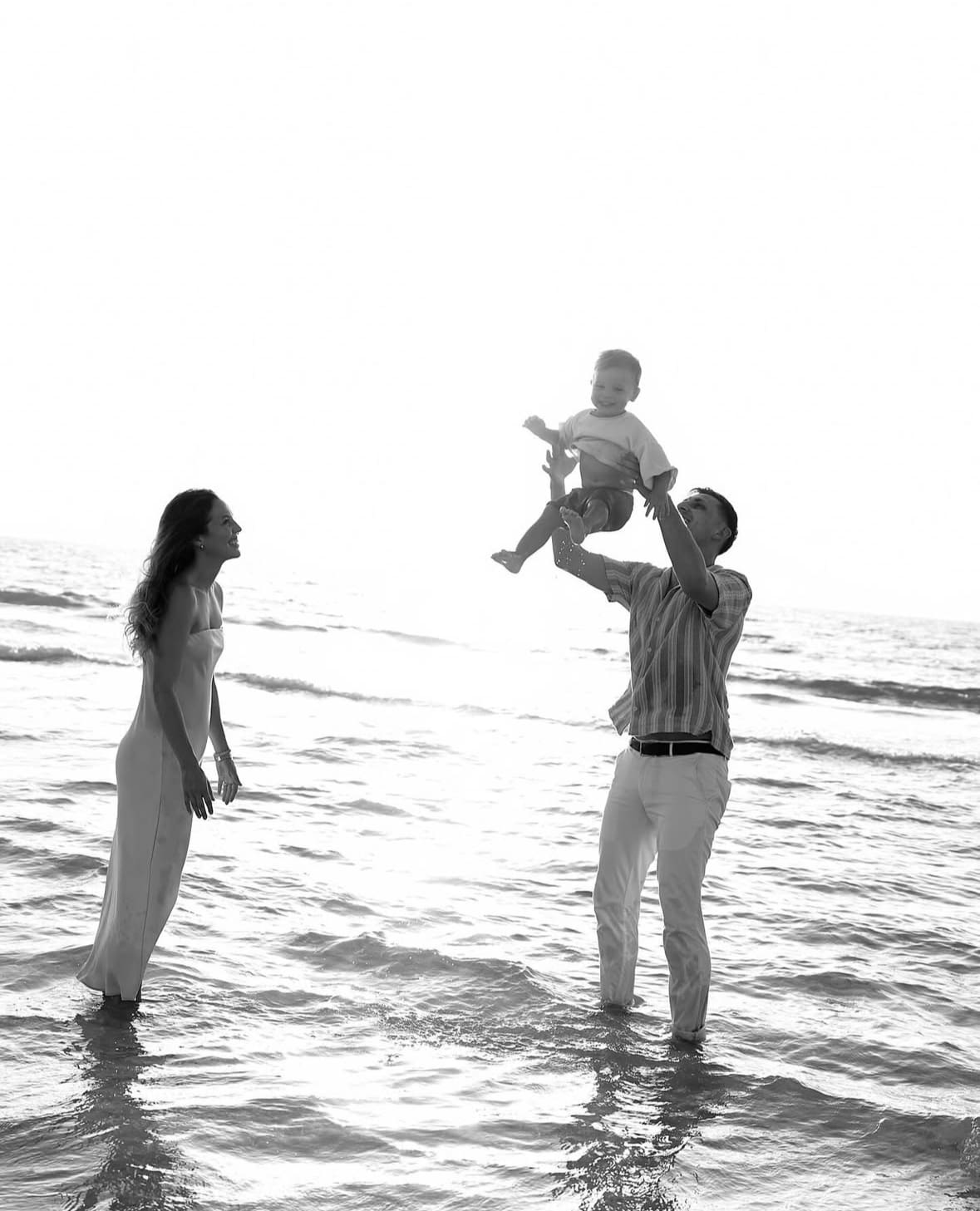 A man holding a young boy and a woman standing next to him