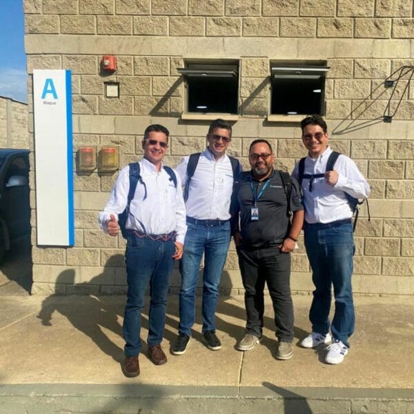 A group of men stand outside a building in the sunshine.