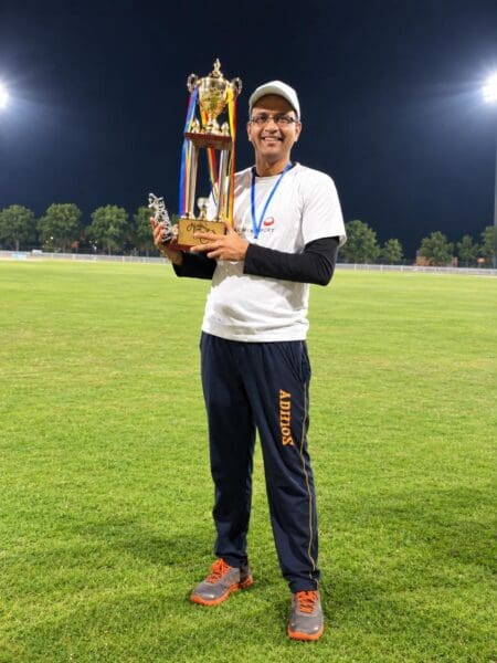 A man hold a trophy for winning a cricket tournament