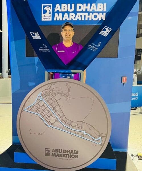 A man stands with a medal for running a marathon